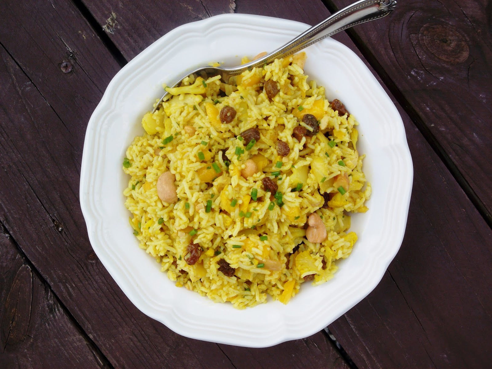 A white plate of yellow rice infused with HANAH Vechur Ghee and mixed with a variety of spices.